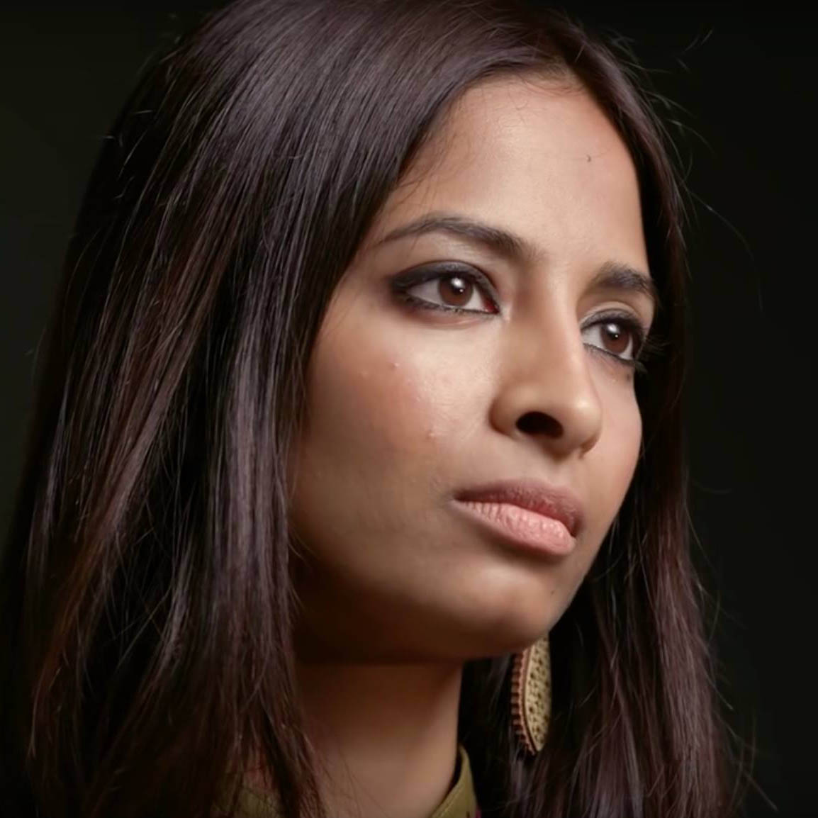 Portrait of Preethi Nallu. She has long, straight black hair. She is wearing long, sophisticated earrings. She is staring in profile.