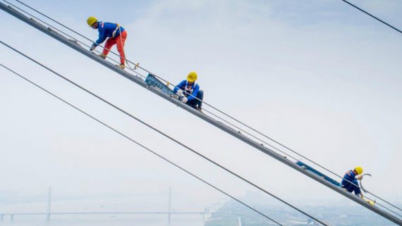 Three construction workers working in a high altitude, in great risk