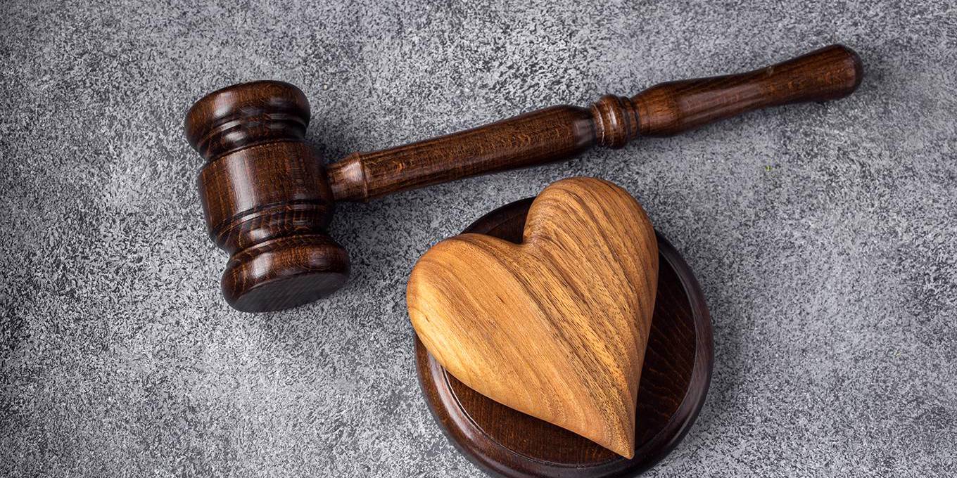 Gavel and wooden heart on concrete gray background. Family law concept